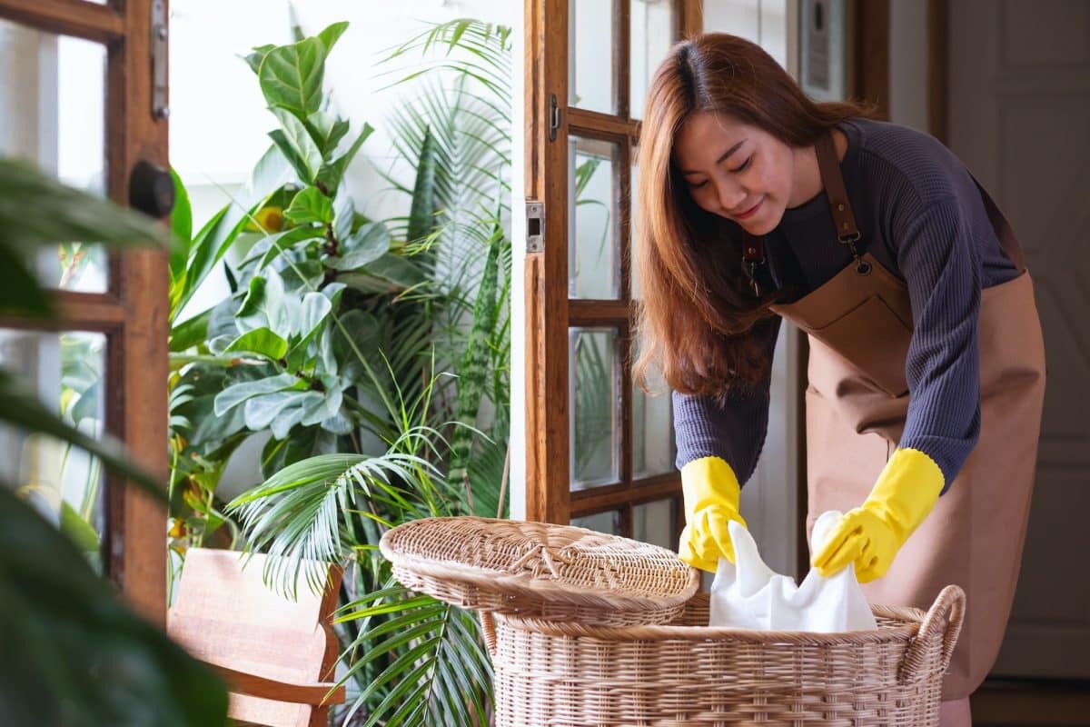 A woman cleaning and putting garbage into the trash bin at home