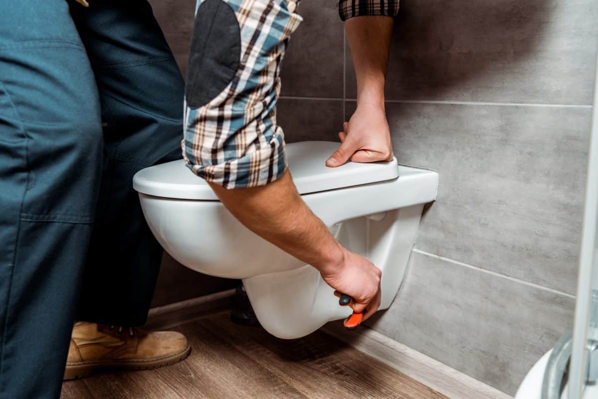 cropped view of installer standing near white toilet