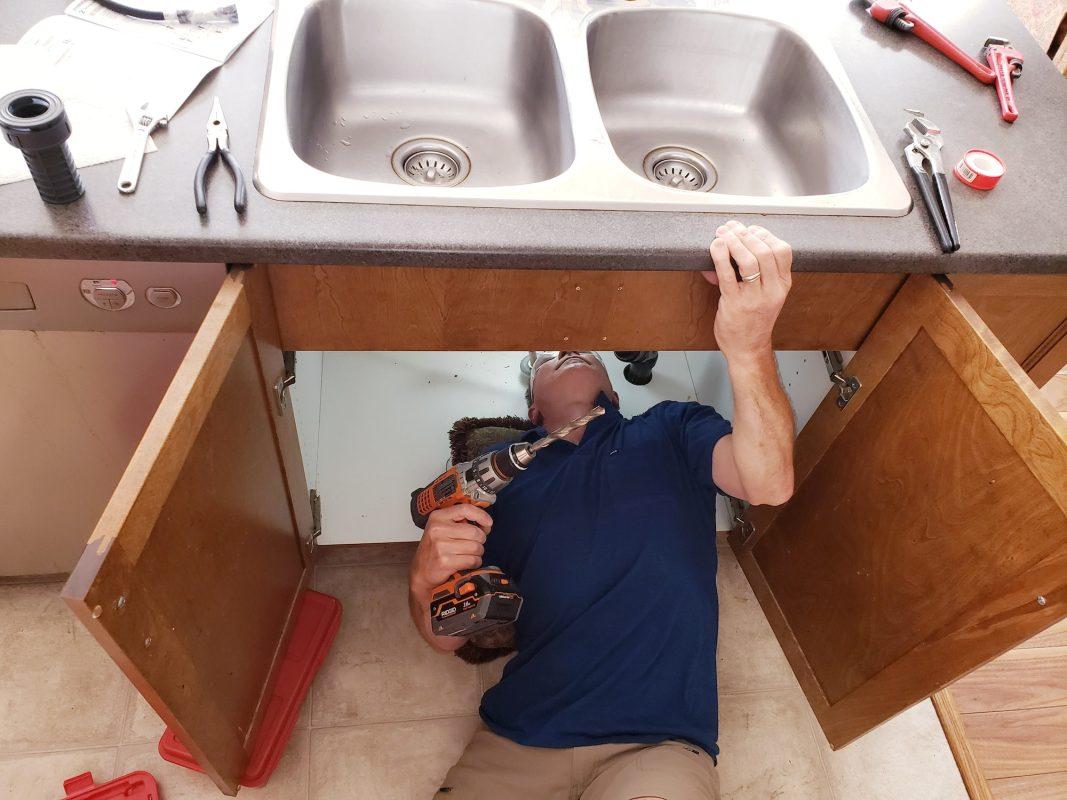 Man is doing repairs on sink plumbing, leaking, faucet