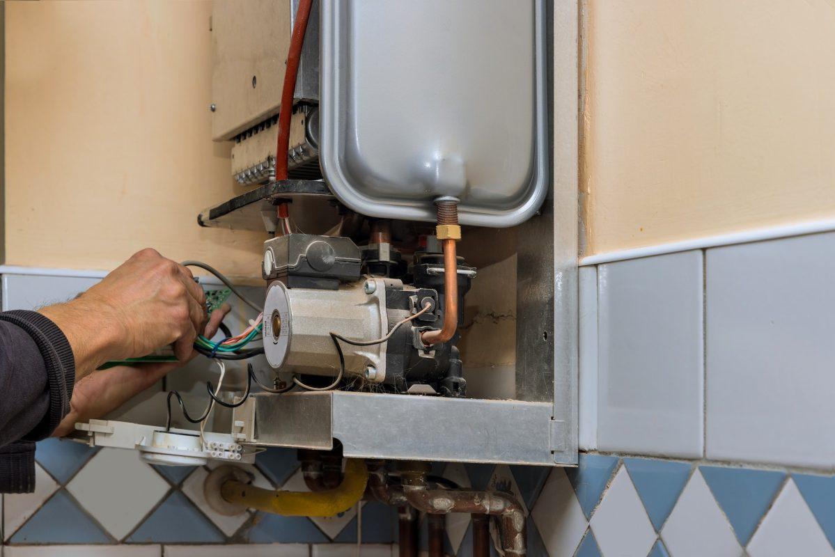 Water heater maintenance service technician repairing gas water heater